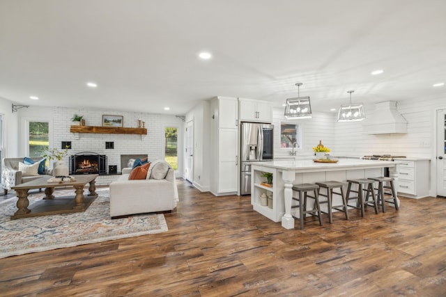 living room featuring plenty of natural light, dark wood-type flooring, brick wall, and a brick fireplace