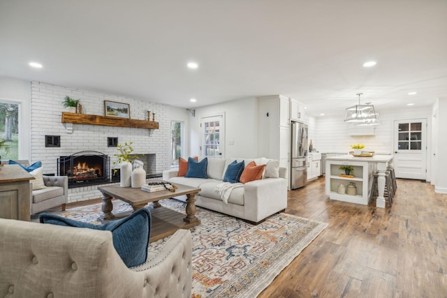 living room featuring a healthy amount of sunlight, light hardwood / wood-style flooring, and a brick fireplace