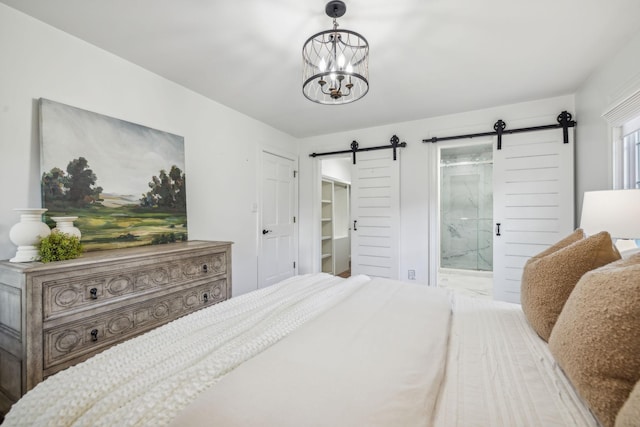 bedroom featuring a barn door, ensuite bath, and a chandelier