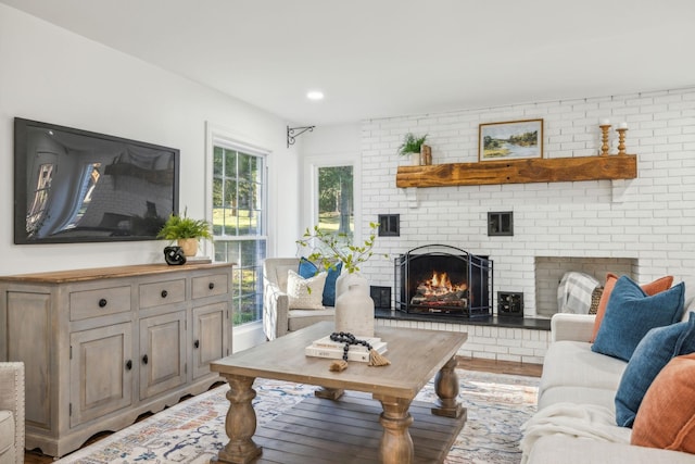 living room with hardwood / wood-style floors, brick wall, and a brick fireplace