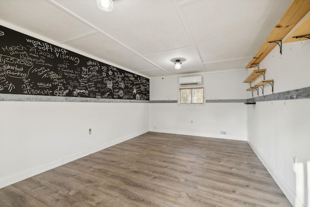 basement featuring hardwood / wood-style flooring and a wall mounted AC