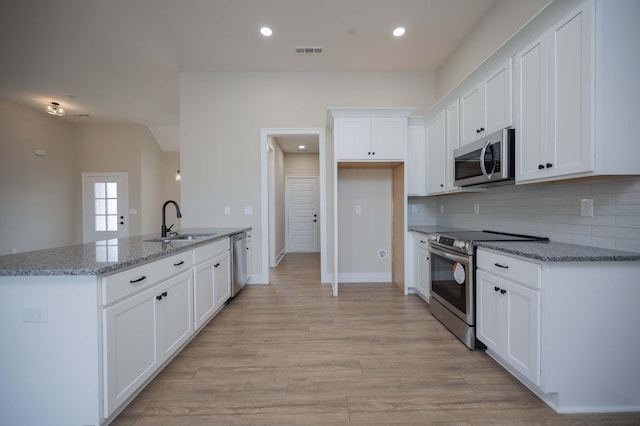 kitchen featuring light stone countertops, appliances with stainless steel finishes, light wood-type flooring, sink, and white cabinets