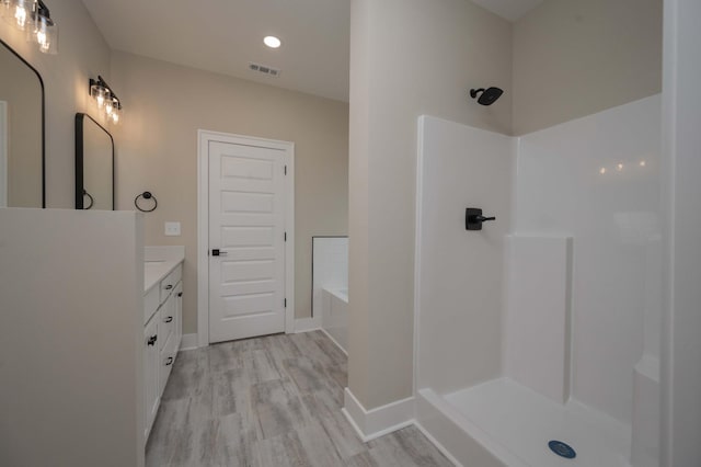 bathroom with walk in shower, vanity, and hardwood / wood-style flooring