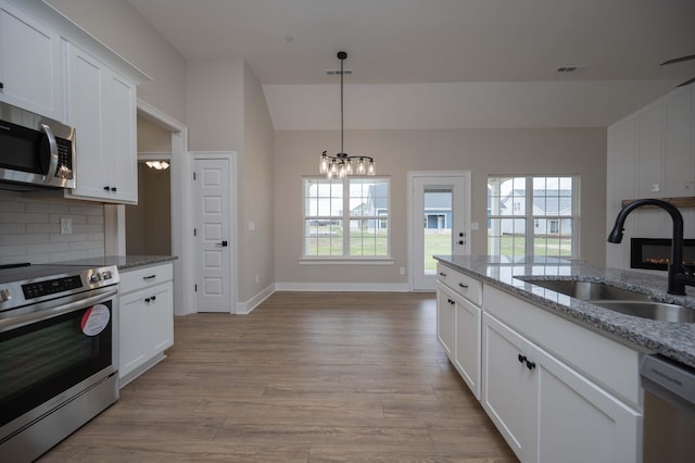 10118 Bighorn Ln, Bell Buckle, TN 37020 - kitchen with appliances with stainless steel finishes, a fireplace, a chandelier, backsplash, and light wood-type flooring