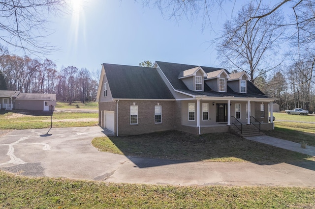 view of front of property featuring a garage, covered porch, and a front lawn