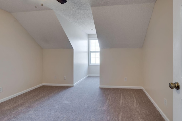 additional living space with carpet flooring, ceiling fan, lofted ceiling, and a textured ceiling