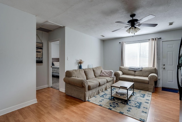 living room with ceiling fan, a textured ceiling, and hardwood / wood-style flooring