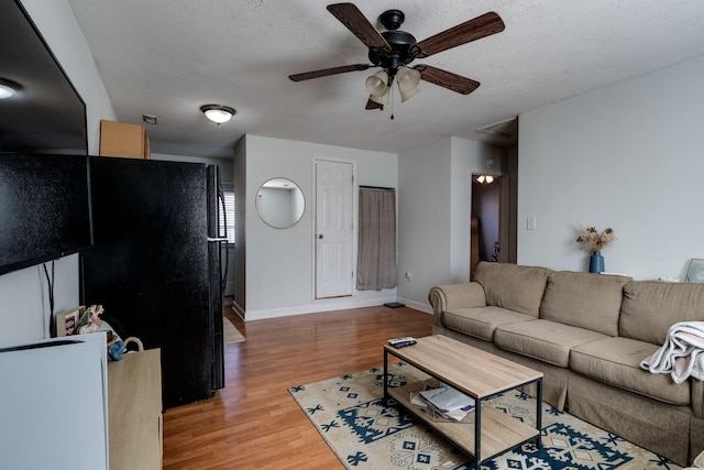 living room with a textured ceiling, light hardwood / wood-style floors, and ceiling fan