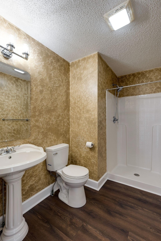 bathroom featuring tiled shower, hardwood / wood-style floors, and a textured ceiling