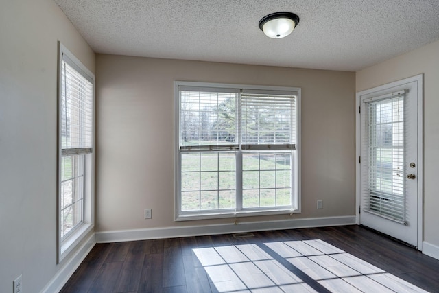 interior space featuring a healthy amount of sunlight, dark hardwood / wood-style flooring, and a textured ceiling