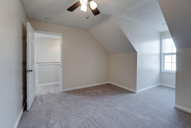 additional living space featuring a textured ceiling, ceiling fan, light carpet, and vaulted ceiling