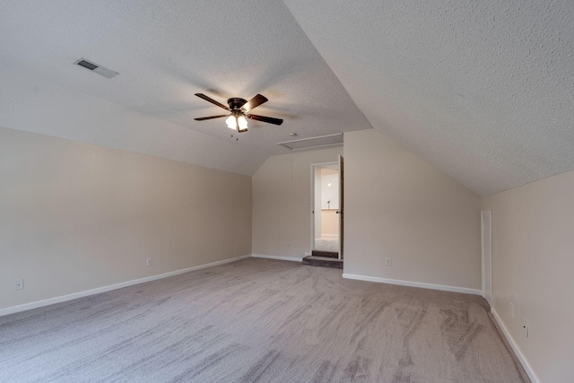 additional living space featuring ceiling fan, a textured ceiling, light carpet, and vaulted ceiling