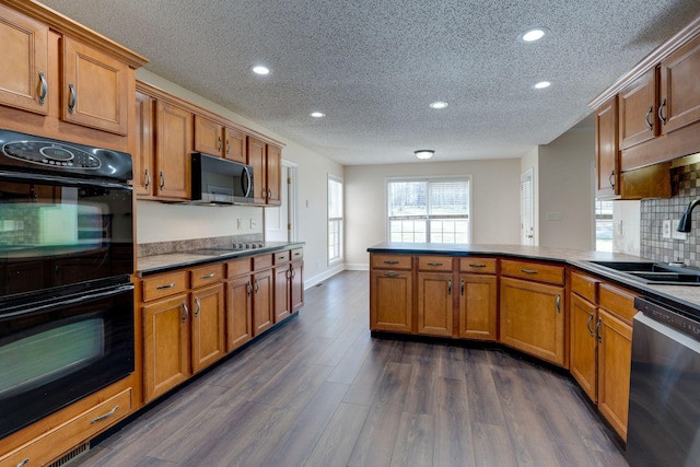 kitchen featuring sink, dark hardwood / wood-style floors, a textured ceiling, kitchen peninsula, and stainless steel appliances