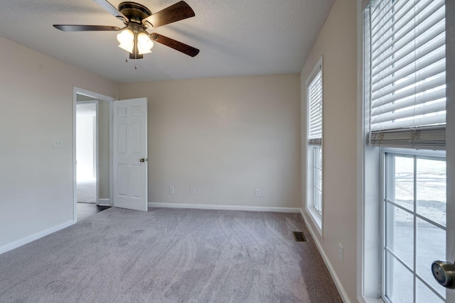 carpeted spare room featuring ceiling fan and a textured ceiling