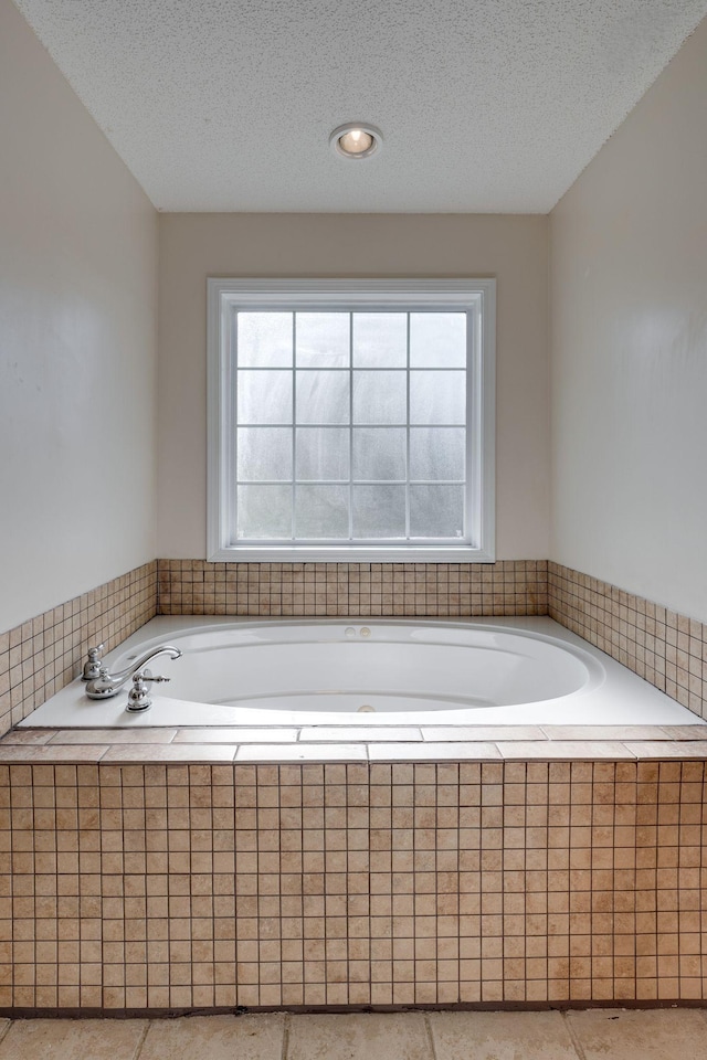 bathroom featuring a textured ceiling and tiled bath