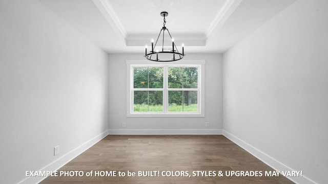 unfurnished dining area featuring a raised ceiling, wood-type flooring, ornamental molding, and a chandelier