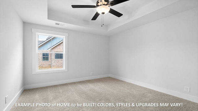 spare room with a raised ceiling, ceiling fan, and carpet