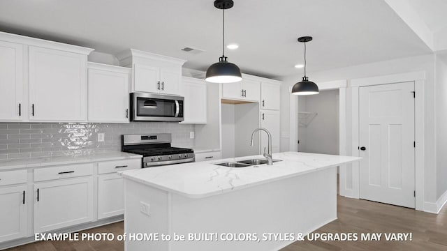 kitchen with sink, stainless steel appliances, light stone countertops, white cabinets, and a center island with sink