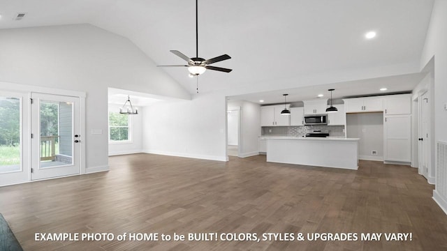 unfurnished living room with high vaulted ceiling, dark hardwood / wood-style flooring, and ceiling fan with notable chandelier