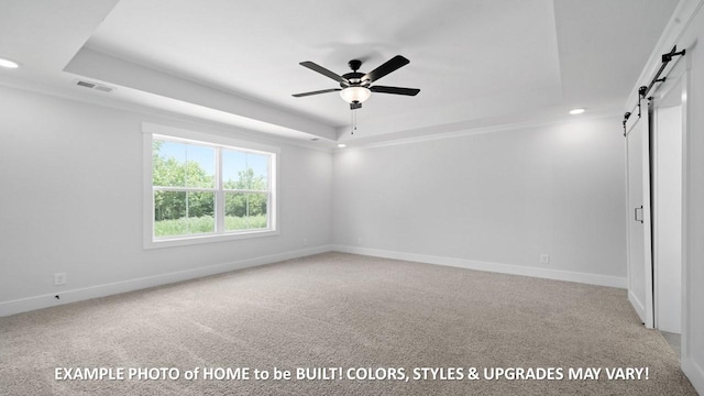 unfurnished room with a raised ceiling, a barn door, light colored carpet, and ceiling fan