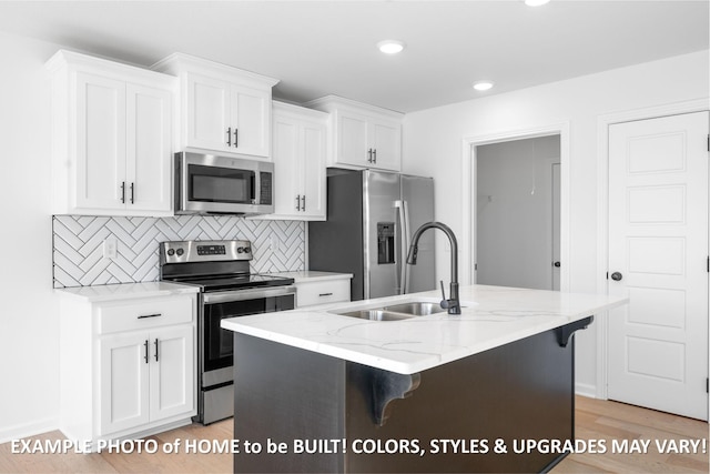 kitchen with an island with sink, appliances with stainless steel finishes, light stone countertops, white cabinetry, and backsplash