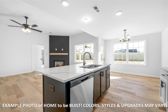 kitchen with an island with sink, light stone counters, stainless steel dishwasher, pendant lighting, and a sink