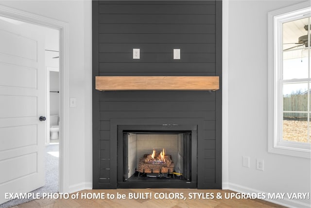 room details featuring a ceiling fan, a large fireplace, and baseboards