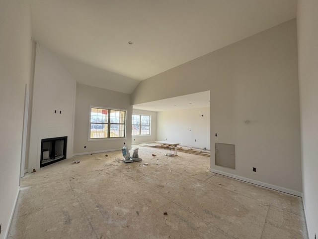 unfurnished living room featuring high vaulted ceiling and a glass covered fireplace