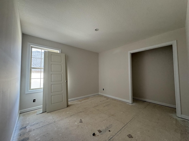 unfurnished bedroom featuring a textured ceiling and baseboards