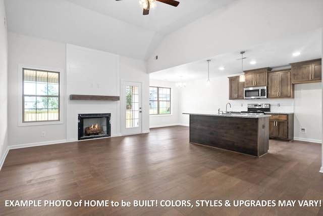 kitchen with dark wood-style floors, open floor plan, a kitchen island with sink, stainless steel appliances, and pendant lighting