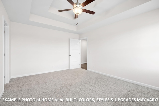 unfurnished bedroom featuring carpet, baseboards, and a raised ceiling