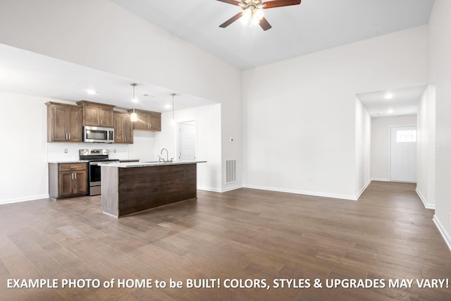 kitchen featuring decorative light fixtures, stainless steel appliances, visible vents, a kitchen island with sink, and a sink