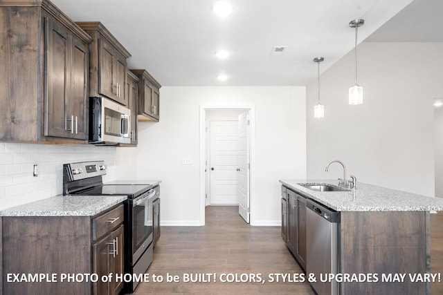 kitchen with appliances with stainless steel finishes, a sink, decorative light fixtures, and light stone countertops