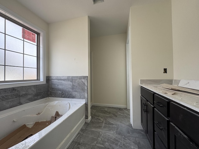 bathroom with marble finish floor, baseboards, a jetted tub, and vanity