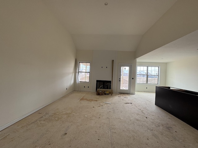 unfurnished living room featuring lofted ceiling, a fireplace, and a wealth of natural light