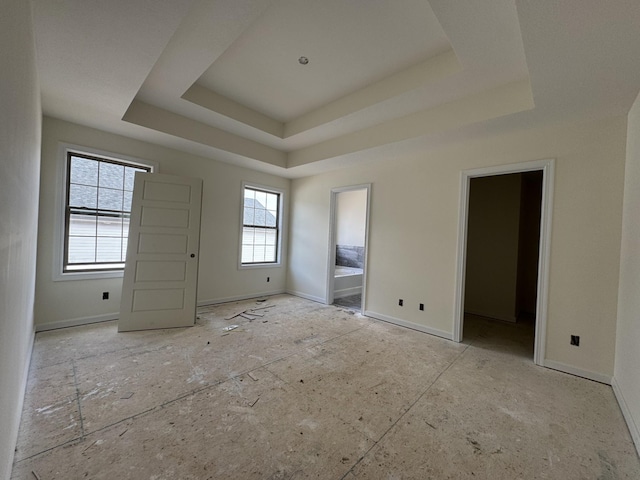 interior space with ensuite bath, a raised ceiling, and baseboards