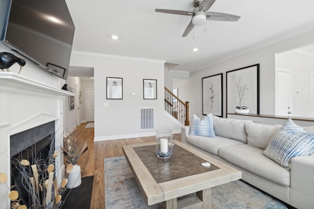 living room with hardwood / wood-style flooring, ceiling fan, and ornamental molding