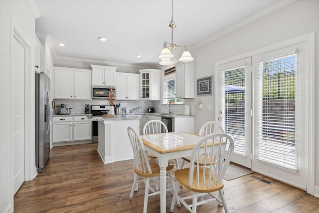 dining room with sink, dark hardwood / wood-style flooring, a notable chandelier, and ornamental molding