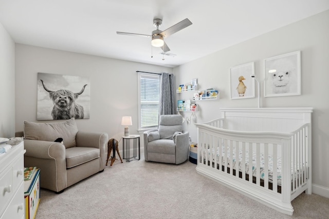 carpeted bedroom with ceiling fan and a crib