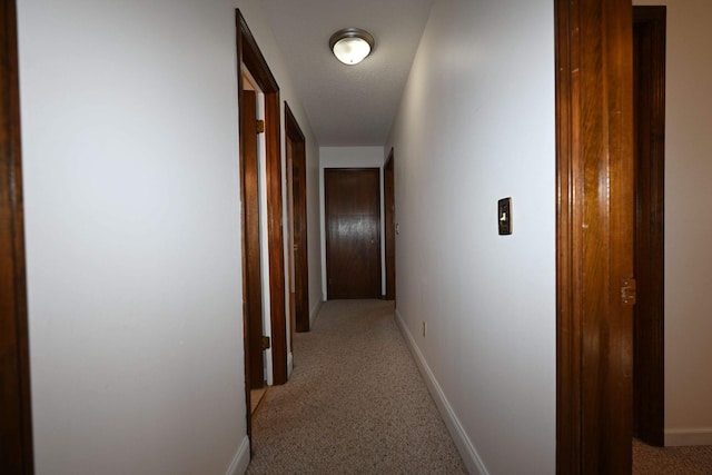 corridor with light carpet and a textured ceiling