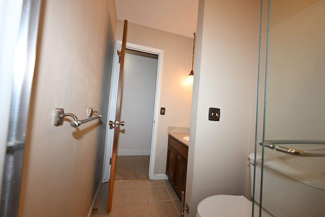 bathroom featuring tile patterned floors, vanity, a shower with shower door, and toilet