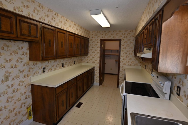 kitchen with white electric range oven, dark brown cabinets, and a textured ceiling