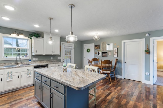 kitchen with a kitchen island, white cabinetry, sink, and dark wood-type flooring