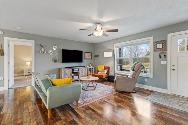 living room with ceiling fan, a healthy amount of sunlight, dark hardwood / wood-style flooring, and a textured ceiling