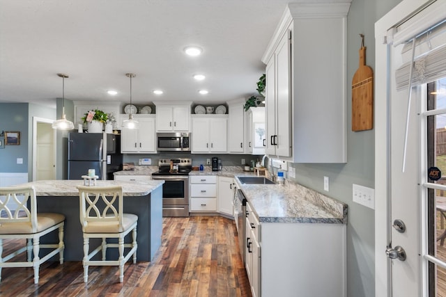 kitchen with a center island, dark hardwood / wood-style floors, decorative light fixtures, white cabinetry, and stainless steel appliances