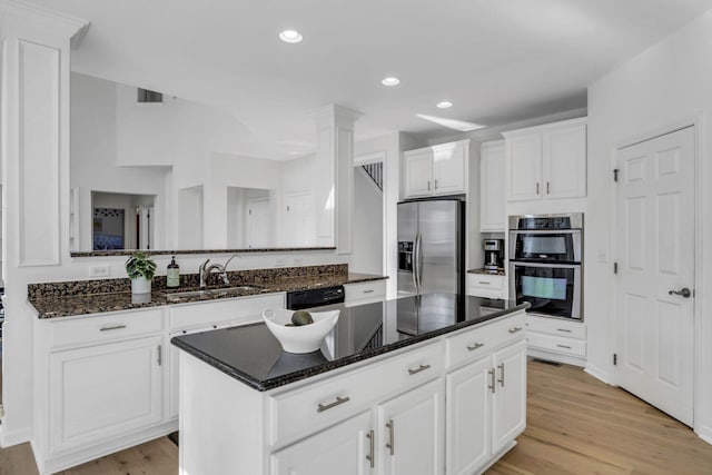 kitchen featuring sink, stainless steel appliances, white cabinets, light hardwood / wood-style floors, and a kitchen island