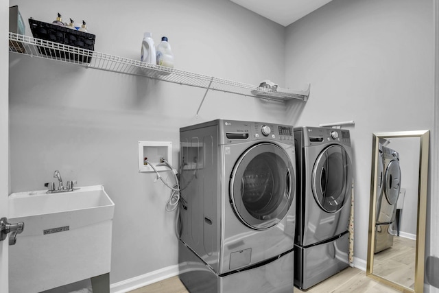 laundry room featuring sink, light hardwood / wood-style flooring, and washing machine and clothes dryer