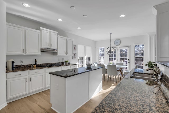 kitchen with white cabinets, decorative light fixtures, light hardwood / wood-style floors, and sink