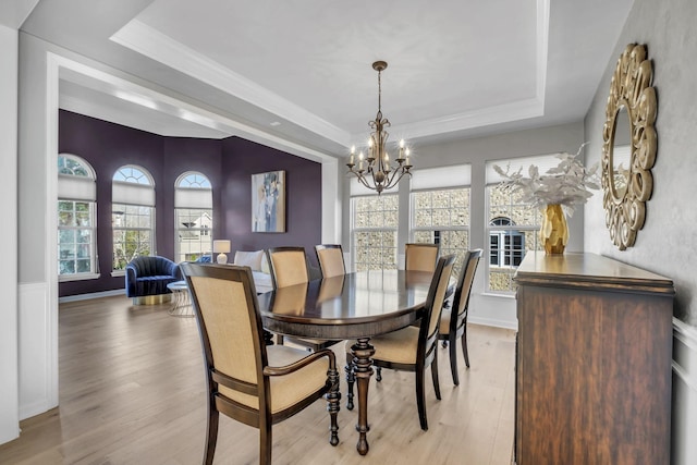 dining room with a tray ceiling, light hardwood / wood-style floors, and an inviting chandelier