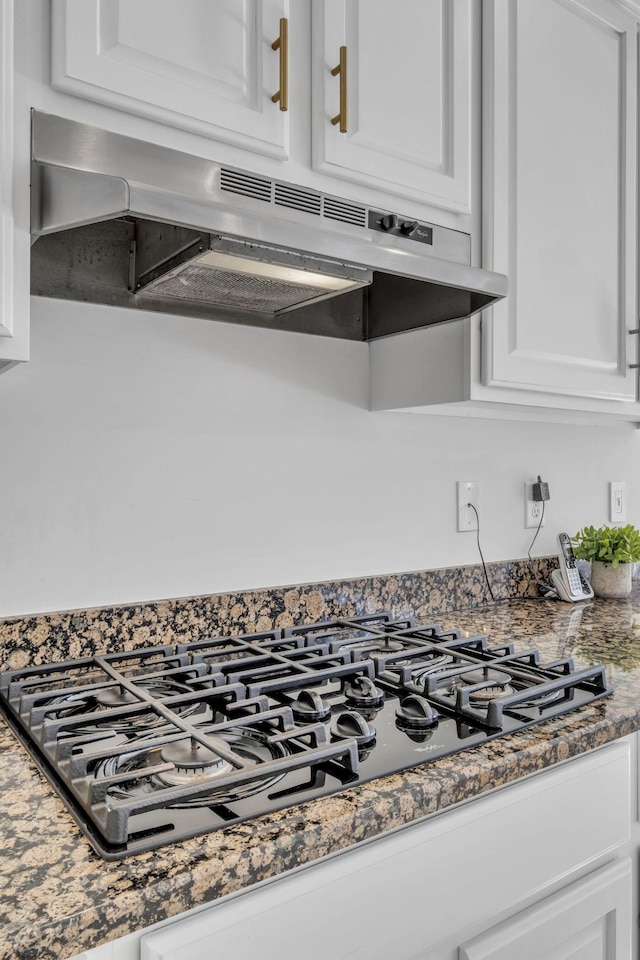 interior details with white cabinets, black gas cooktop, and dark stone counters